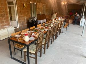 una larga mesa de madera con sillas y comida. en Karine B&B en Yeghegnadzor