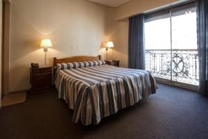 a bedroom with a bed and a large window at Hotel Marbella in Buenos Aires