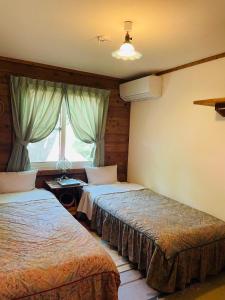 高森町にあるペンション　山林舎のベッド2台と窓が備わるホテルルームです。
