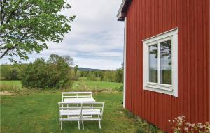 zwei weiße Bänke vor einem roten Gebäude in der Unterkunft 2 Bedroom Nice Home In motfors in Åmotsfors