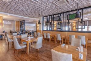Port River Hotel&Spa في سيدي: مطعم بطاولات خشبية وكراسي بيضاء