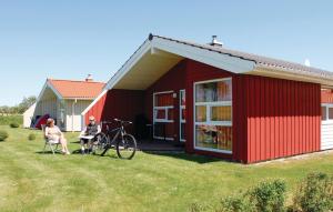 a couple of people sitting outside of a red house at Friedrichskoog-Strandpark 9 in Friedrichskoog