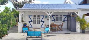 a white house with blue chairs and a table at Agréable maison 3 pièces tout confort pour 4 personnes - Vue sur jardin in Saint-François