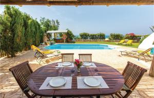 a wooden table with four chairs and a pool at Gorgeous Home In Pomos in Pomos