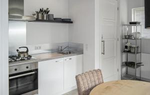 eine Küche mit weißen Schränken und einem Waschbecken und einem Tisch in der Unterkunft Berg En Zee 3 in Bergen aan Zee
