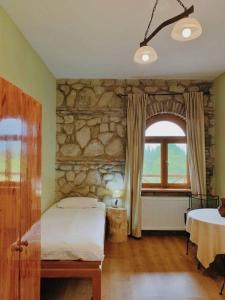 a bedroom with a bed and a stone wall at Elizbar Talakvadze Winery in Kardanakhi