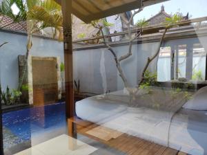 a room with a bed and a tree in it at Villa Sahabat in Gili Trawangan