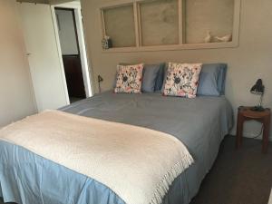 a bedroom with a large bed with two pillows at Serendipity Wharf Cottage in Tairua