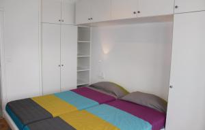- une chambre avec un lit arc-en-ciel et des armoires blanches dans l'établissement Residentie Acapulco 6B, à Ostende