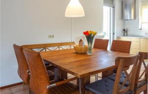 una mesa de comedor de madera con sillas y un jarrón de flores en Oesterbaai - 8 Personen, en Wemeldinge