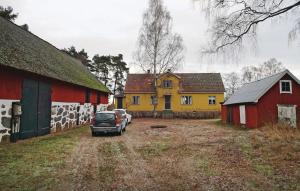 une voiture garée dans un champ à côté de deux bâtiments dans l'établissement 2 Bedroom Amazing Home In Slvesborg, à Möllebjörke