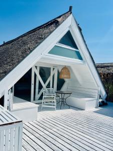 ein weißes Haus mit einem Tisch und Stühlen auf einer Terrasse in der Unterkunft Seehütte Strandhaus direkt im Neusiedler See in Rust