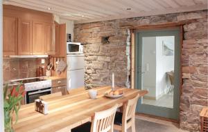 uma cozinha com uma mesa de madeira e uma parede de pedra em Awesome Home In Kpingsvik With Kitchen em Köpingsvik