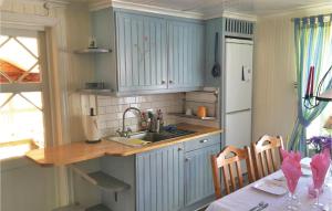 cocina con armarios azules, fregadero y mesa en 2 Bedroom Stunning Home In Hgster, en Högsäter