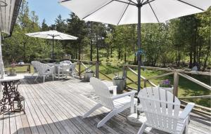 a deck with white chairs and an umbrella at Nice Home In Lrbro With 2 Bedrooms And Wifi in Slite