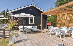 a wooden deck with tables and chairs and an umbrella at Nice Home In Lrbro With 2 Bedrooms And Wifi in Slite