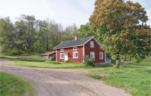 a red barn on a dirt road next to a tree at 2 Bedroom Nice Home In senhga in Åsenhöga