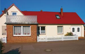 ein Haus mit rotem Dach und einem weißen Zaun in der Unterkunft Awesome Apartment In Elmenhorst-lichtenhag, With Kitchenette in Elmenhorst