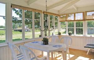 uma sala de jantar com mesa, cadeiras e janelas em Nice Home In Burseryd With Sauna em Burseryd