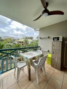 a balcony with a table and chairs and a kitchen at Ti Studio Creole Mahogany in Sainte-Anne