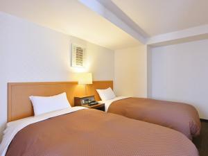 a room with two beds and a clock on a table at Hotel Sun Okinawa in Naha