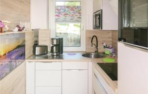 eine Küche mit weißen Schränken, einem Waschbecken und einem Fenster in der Unterkunft Ferienhaus Waldgrundst�ck P in Mehltheuer