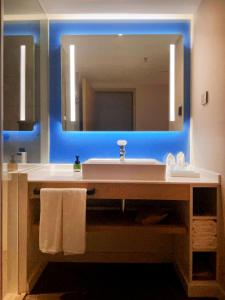 uma casa de banho com um lavatório e um espelho grande em Holiday Inn Express Hohhot East Station, an IHG Hotel em Hohhot