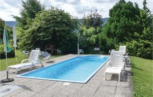 a swimming pool with two chairs and a table at Lovely Apartment In Sattendorf With Lake View in Sattendorf