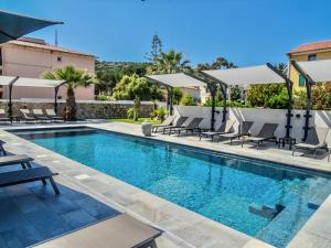 a swimming pool with chairs and umbrellas next to a house at Maria Stella in LʼÎle-Rousse