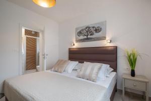 a bedroom with a bed with white sheets and a tree picture on the wall at Villa Mirta in Bol +23 photos