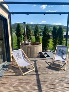dos sillas sentadas en una terraza con una hoguera en Małe Formy - drewniany domek w górach z balią en Kamienna Góra