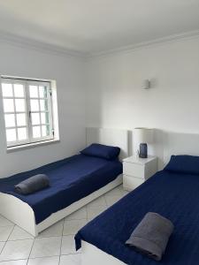 een witte slaapkamer met 2 bedden en een raam bij Relaxing 2 Bedroom House 5 minutes away from Vilamoura Marina in Quarteira