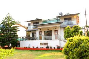 a house with a balcony and a tree at Dream House Mahabaleshwar in Mahabaleshwar
