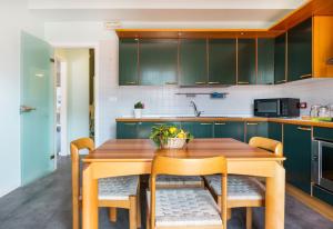 une cuisine avec des placards verts et une table en bois avec des chaises dans l'établissement G House Apartment, à Sorrente