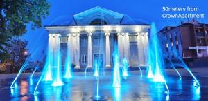 a building with a fountain in front of it at Crown Apartment in Ukmergė