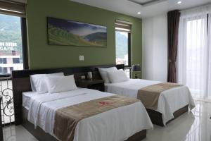 two beds in a room with green walls and windows at Phúc Lâm Hotel in Ha Giang