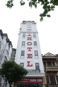 a tall white building with a red sign on it at Phúc Lâm Hotel in Ha Giang
