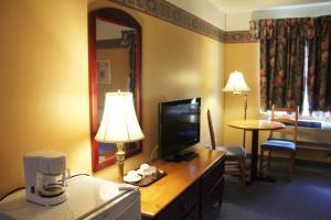 a hotel room with a desk with a television and a room at Hôtel Le Portneuvois in Portneuf