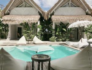 a pool with chairs and a table in front of a building at Gravity Eco Boutique Hotel - Adults Only in Uluwatu