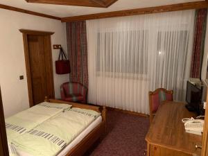 a bedroom with a bed and a desk and a table at Hotel Haus Tiefenbach in Bullange