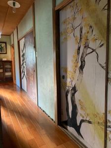 un pasillo con un mural de un árbol en la pared en Hanatsu, en Tamano