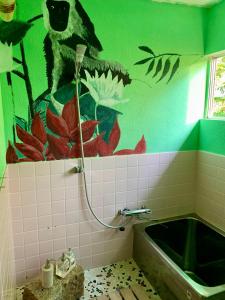 a bathroom with a bath tub and a green wall at Hanatsu in Tamano