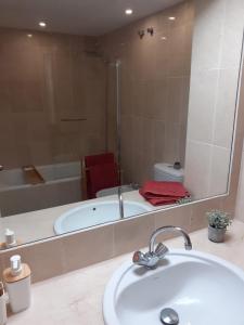łazienka z wanną, umywalką i lustrem w obiekcie Estepona Golf Apartment w mieście Estepona
