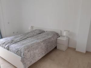 biała sypialnia z łóżkiem i stolikiem nocnym w obiekcie Estepona Golf Apartment w mieście Estepona +20 zdjęć