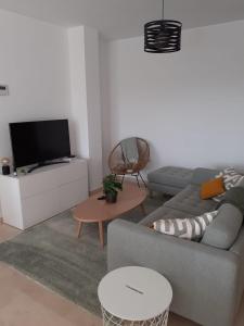 ein Wohnzimmer mit einem Sofa und einem TV in der Unterkunft Estepona Golf Apartment in Estepona