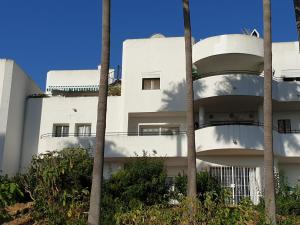 a white building with palm trees in front of it at Estepona Golf Apartment in Estepona