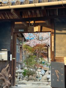 an entrance to a building with a garden with a tree at Hanatsu in Tamano