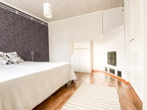 1 dormitorio con 1 cama blanca grande y 1 alfombra en Maalaistalo maatilamiljöössä, en Haapavesi