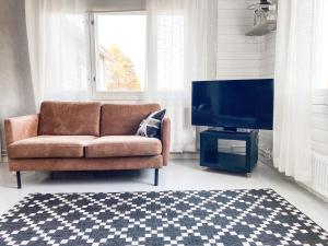 ein Wohnzimmer mit einem Sofa und einem Flachbild-TV in der Unterkunft Maalaistalo maatilamiljöössä in Haapavesi