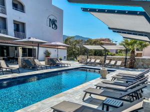 a swimming pool with lounge chairs and a hotel at Maria Stella in LʼÎle-Rousse